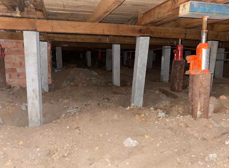 Hydraulic jack holding the floor while old timber stumps are replaced – underpinning and reblocking in Lorne
